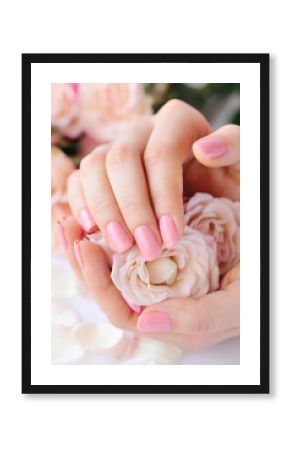 Hands of a woman with pink manicure on nails and roses