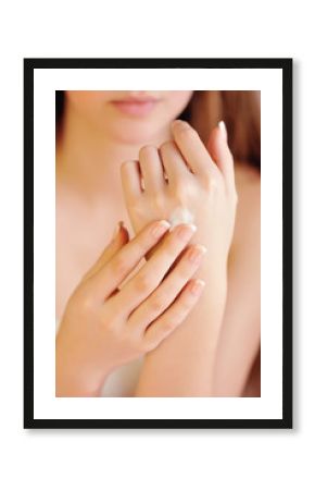 Young woman applies cream on her hands after bath. Focus on hand