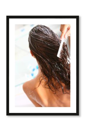 femme dans sa salle de bain soignant ses cheveux