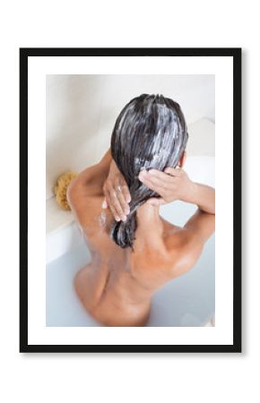 femme dans son bain appliquant une crème sur ses cheveux