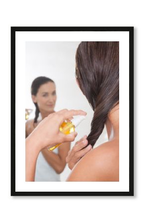 femme qui applique de l'huile sur les pointes de ses cheveux