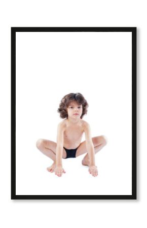 The curly-haired boy in a bathing suit sits in a pose of a frog looking at the camera. Blue background.