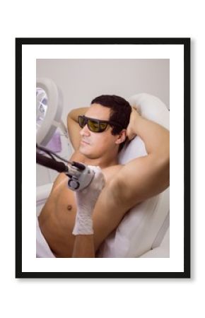 Doctor performing laser hair removal on male patient skin