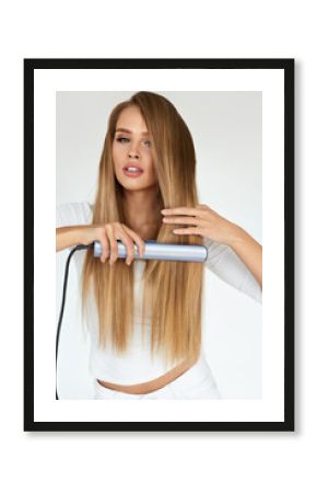 Hairdressing. Woman With Beautiful Long Hair Using Straightener