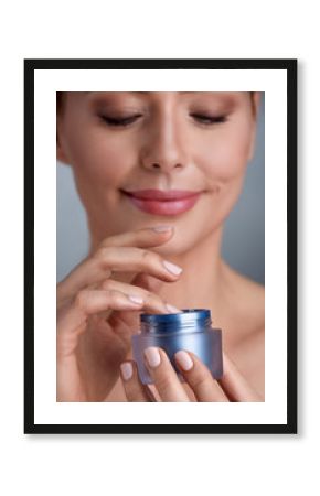 Smiling woman using cosmetic cream