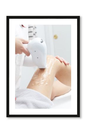 Young woman having legs laser hair removal treatment in salon