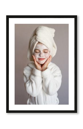Funny little girl with a mask for skin face and with a towel on her head, portrait on a gray background