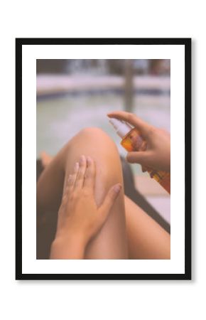 Woman applying sunblock cream on her legs.