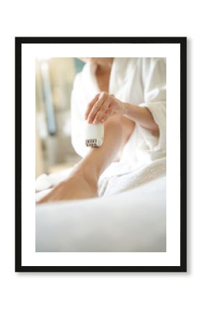 Woman in bedoom shaving legs with electric razor