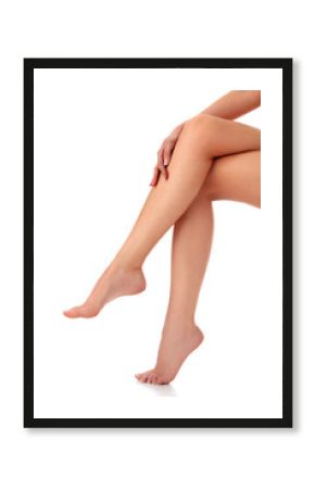 Closeup shot of beautiful female legs and hands. Woman touches her smooth skin with french manicured hands. Isolated on white background