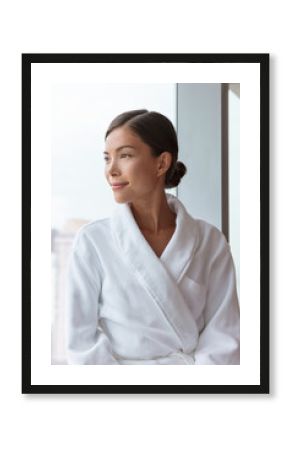 Asian woman relaxing at luxury hotel spa wearing bathrobe looking at window portrait. Pampering comfort lifestyle at resort.