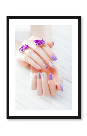 Pastel manicure with earrings on white background. Combination of purple, white, pink colors and sparkles.