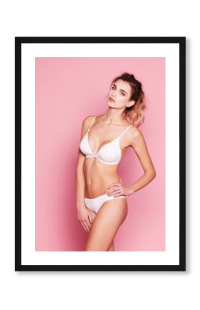 Beautiful woman in white lingerie on a pink background