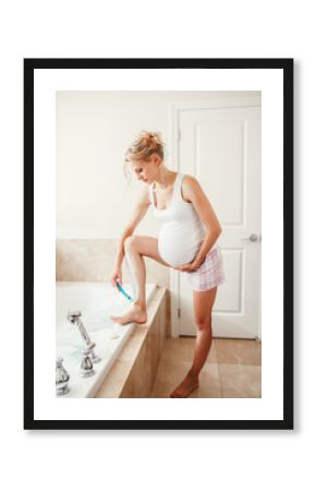 Problems and difficulties during pregnancy. Portrait of pregnant blonde Caucasian woman shaving legs in bathroom. Expecting mom doing cosmetological procedures in the morning.