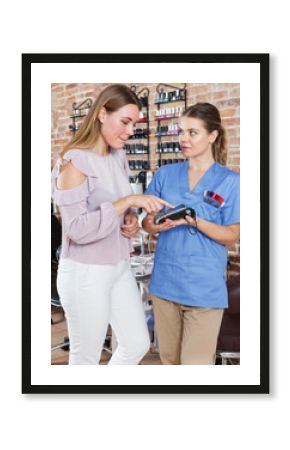 Manicure salon worker helping to client with payments in salon