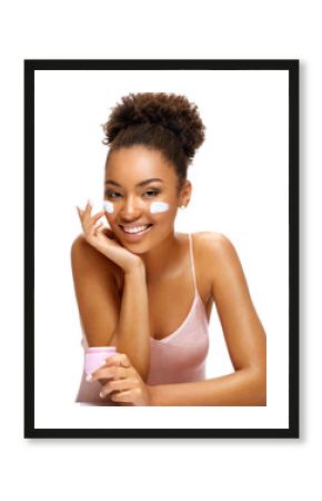 Young girl with moisturizing cream on her face. Photo of smiling african american girl isolated on white background. Beauty & Skin care concept