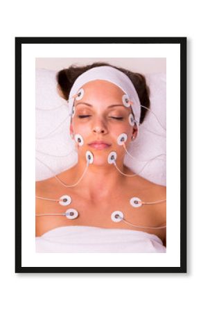 Portrait of a young woman lying  with electrodes on her face