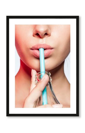 Сlose-up of a girl with a bottle of soda and drinking straw