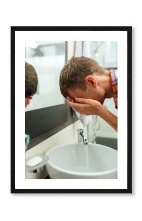 man washes his face with spray