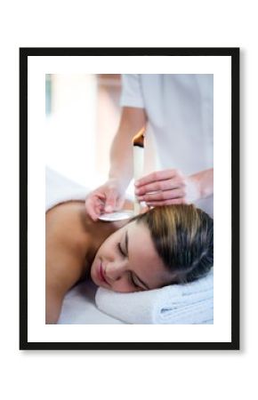 Woman receiving ear candle treatment