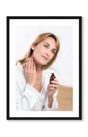 belle femme s'applicant de l'huile essentielle dans le cou