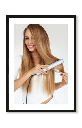 Hairdressing. Woman With Beautiful Long Hair Using Straightener