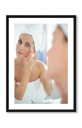 portrait of woman in bathroom applying moisturizing cream