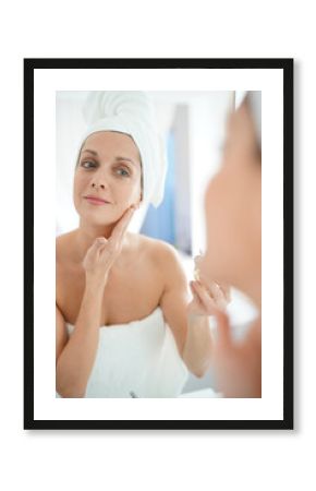 portrait of woman in bathroom applying moisturizing cream