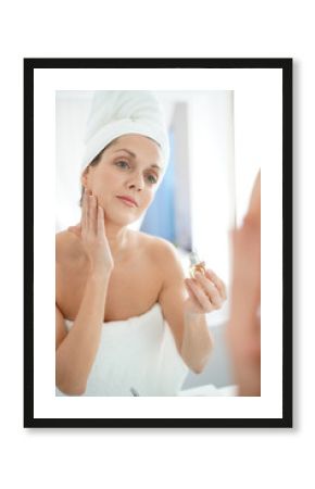 portrait of woman in bathroom applying moisturizing cream