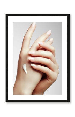 Young woman putting cream on her hand