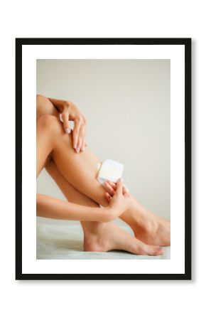 Beautiful woman doing depilation for her legs with waxing strip