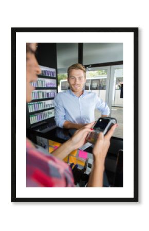hairdresser with male client paying over electronic reader at counter