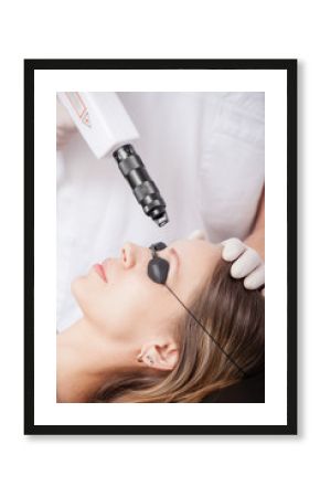 woman during face laser therapy in cosmetics