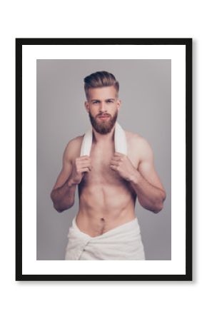 Vertical portrait of handsome neat serious attractive stunning sportive sexy muscular man with modern hairdo white towel on hips holding small towel on neck isolated on gray background