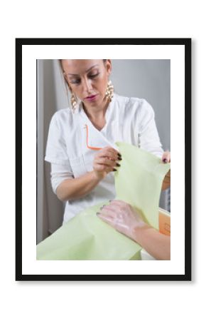 Skin And Hand Care - Beautician Wrapping Female Hand Covered With Paraffin Wax In Green Towel Close Up