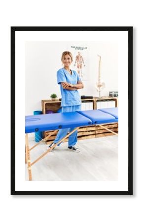 Young caucasian physio therapist smiling happy standing with arms crossed gesture at the clinic