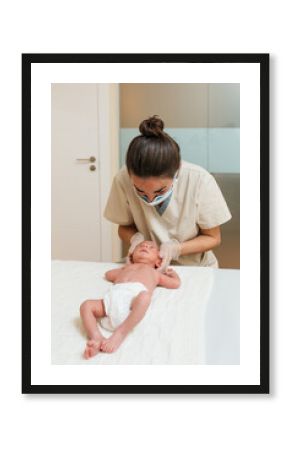 Female physiotherapist doing a positional plagiocephaly correction on a newborn baby in a therapy center.