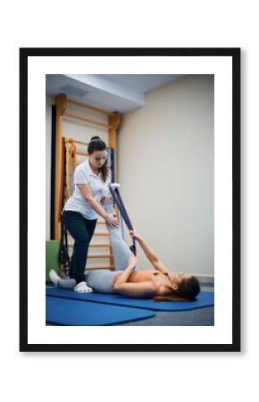 Physical therapist assists her patient with exercising at health club.