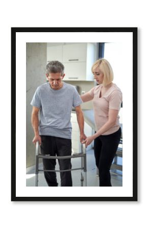 Senior man using a walker with the assistance of a nurse