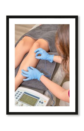 Professional physiotherapist performing therapeutic percutaneous electrolysis treatment on patient's leg using medical equipment and technology