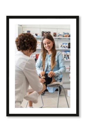 Orthopedist woman putting a knee brace on a young client