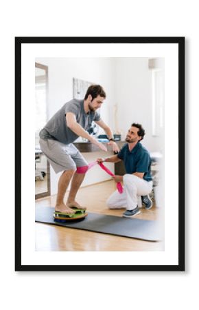 Physiotherapist assisting patient, practicing on balance trainer