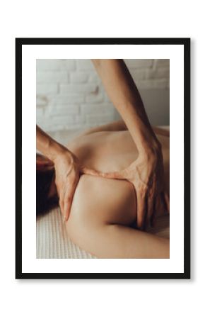 Hands of female chiropractor massaging shoulders of young woman lying on massage table. Concept of physical therapy treatment ,neck pressure point