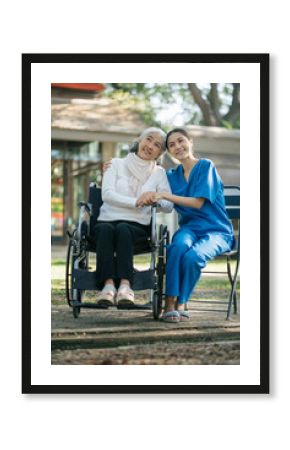 Smiling physiotherapist taking care of the happy senior patient in wheelchair, outdoor.