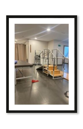 A well-equipped physical therapy room with various rehabilitation equipment, including parallel bars and therapy mats. 