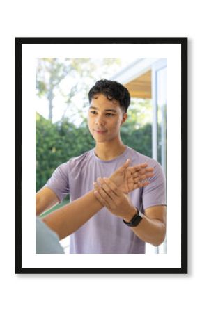 At home, young biracial male physiotherapist assisting a senior female patient