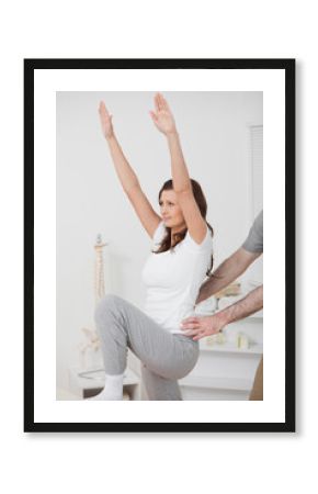 Woman doing exercise while a man is putting his hands on her hip