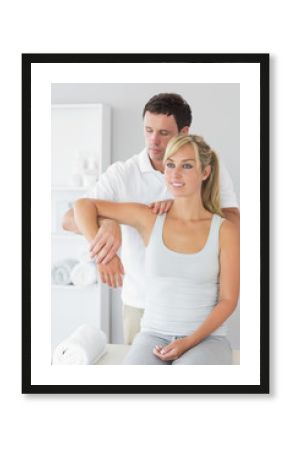 Good looking physiotherapist controlling patients arm