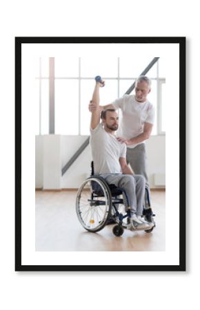 Athletic disabled man training with the coach in the gym