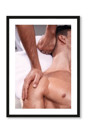 two young man, 20-29 years old, sports physiotherapy indoors in studio, photo shoot. Physiotherapist massaging mans back.
